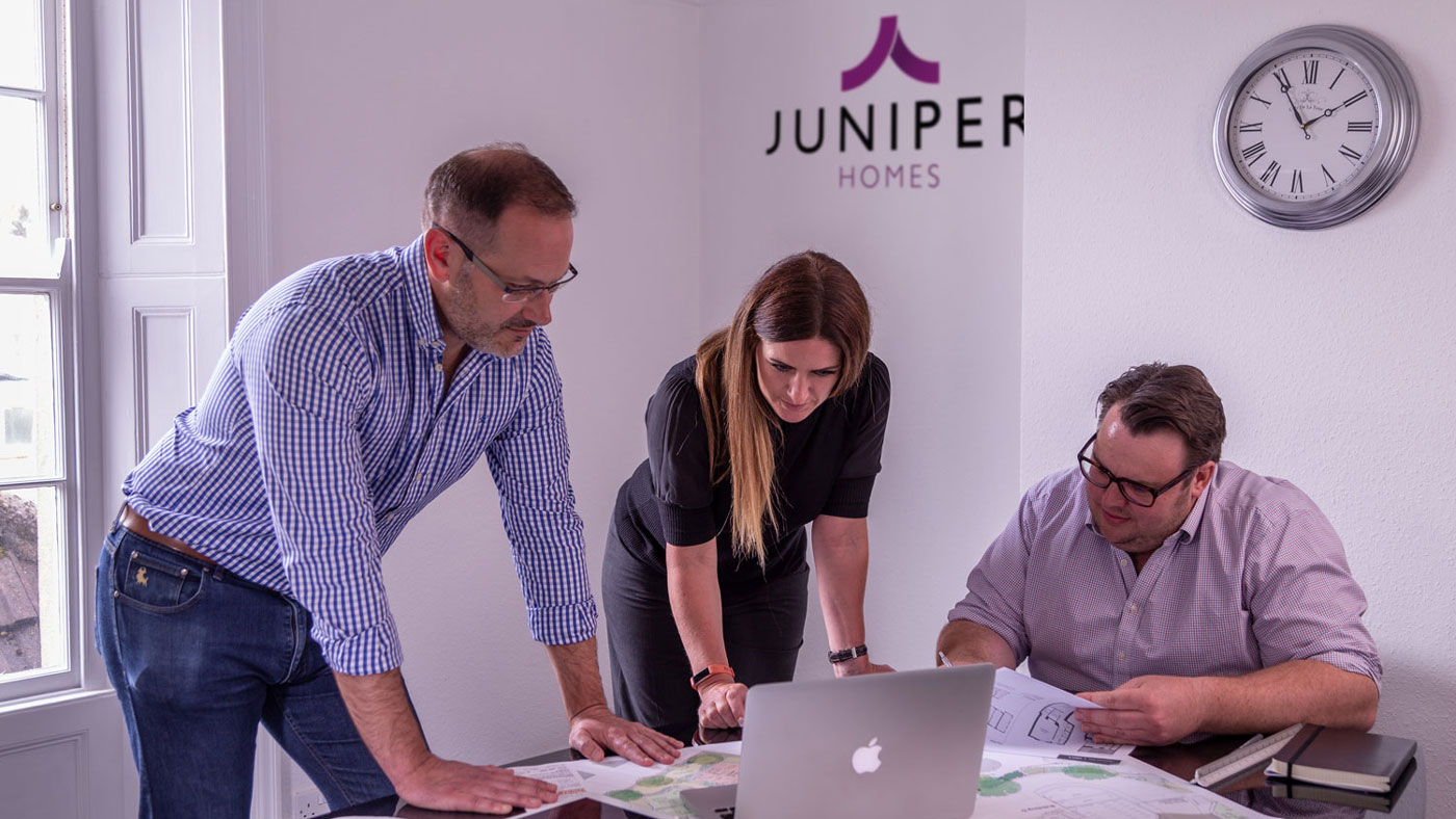 Shot of the Juniper team around a table looking at plans