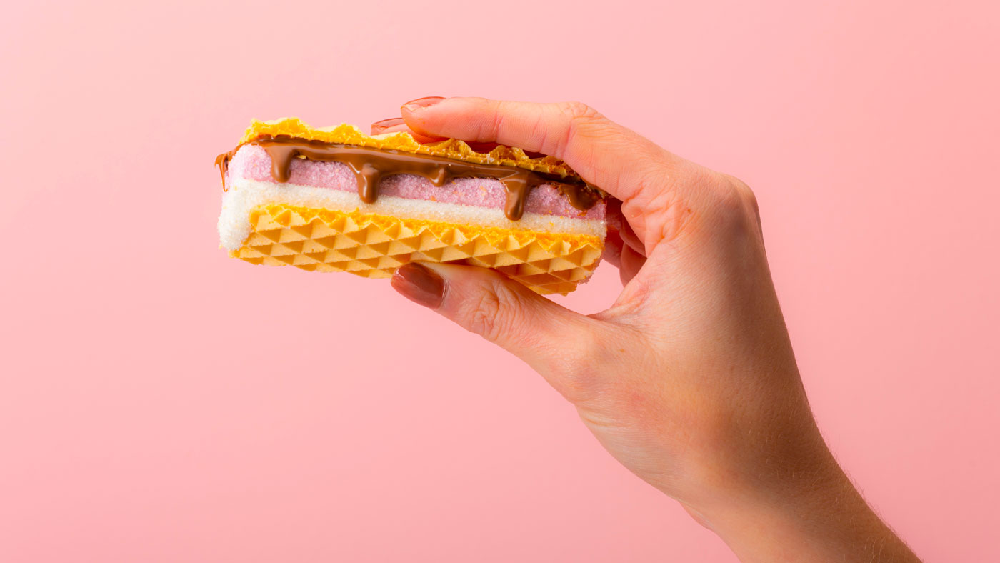 A hand holding a wafer with chocolate running down the side